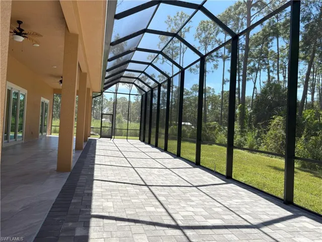 Unfurnished sunroom with a ceiling fan, a patio, and lofted ceiling