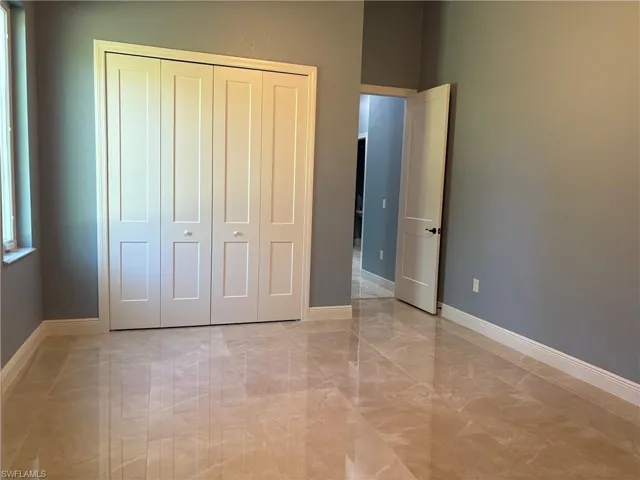 Unfurnished bedroom featuring light marble finish floors and a closet