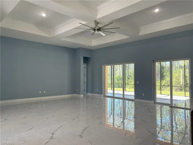 Spare room featuring light marble finish floors, beamed ceiling, coffered ceiling, ornamental molding, and a ceiling fan