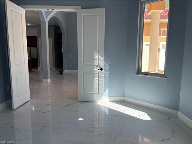 Spare room featuring arched walkways and light marble finish floors