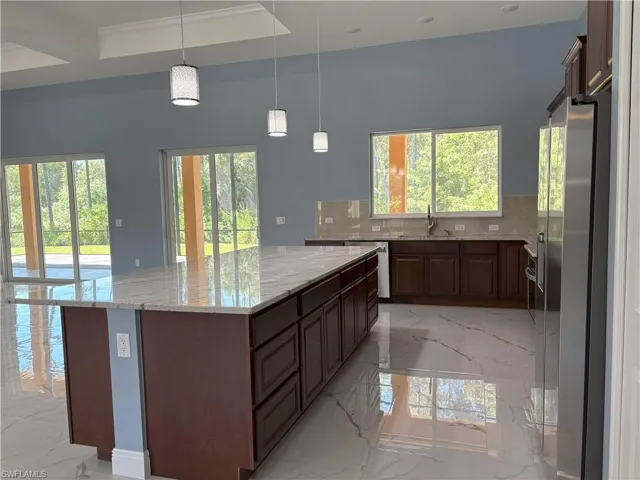 Kitchen with light stone countertops, light marble finish flooring, decorative backsplash, pendant lighting, and recessed lighting