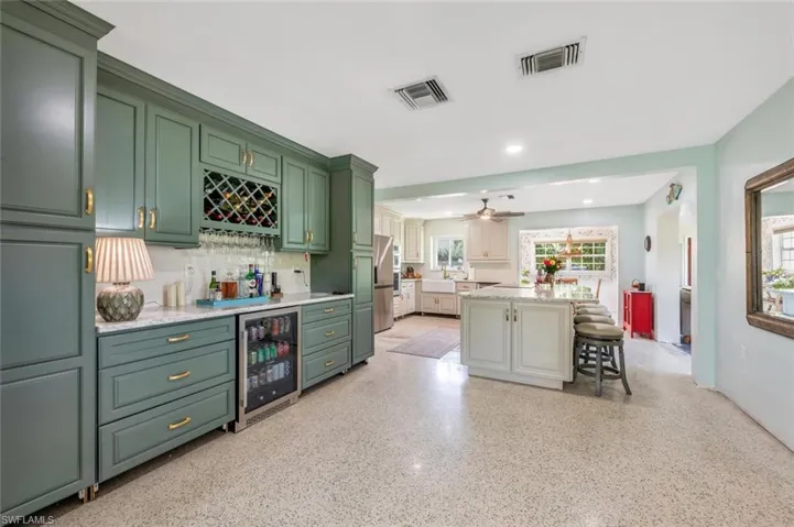 Kitchen featuring green cabinets, a kitchen bar, wine cooler, a healthy amount of sunlight, and a kitchen island