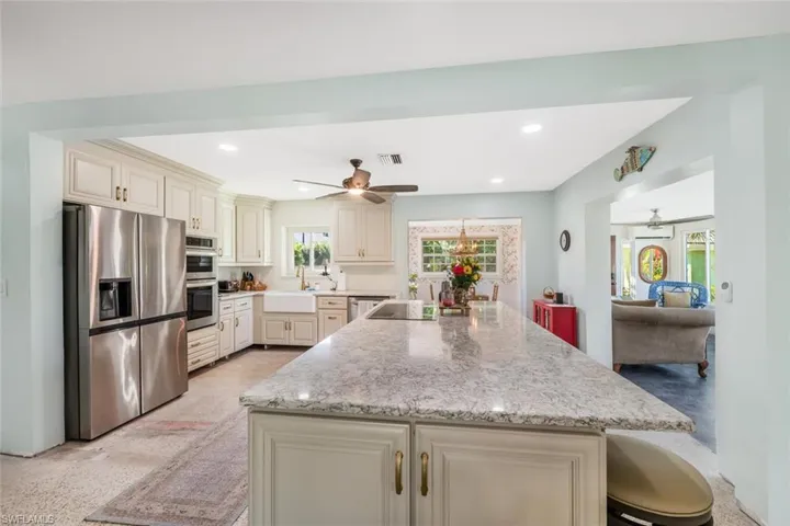 Kitchen with sink, a breakfast bar, appliances with stainless steel finishes, light stone countertops, and cream cabinetry