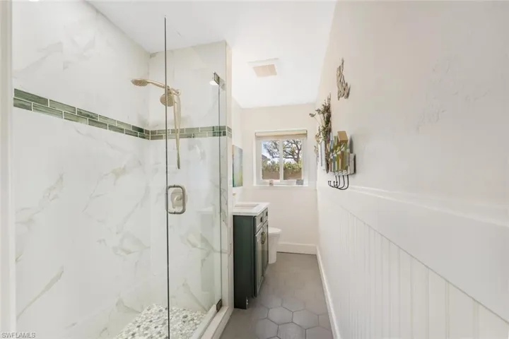 Bathroom featuring vanity, a shower with door, and toilet