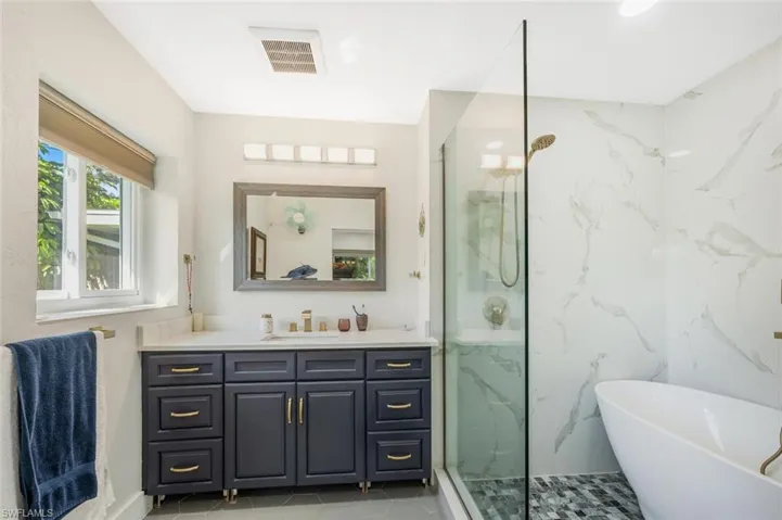 Bathroom featuring tile patterned flooring, vanity, and separate shower and tub