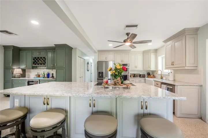 Kitchen with light stone counters, stainless steel appliances, a center island, and a breakfast bar