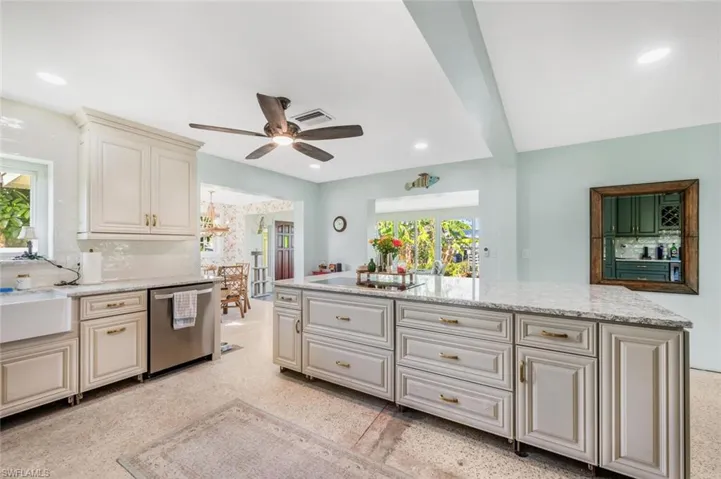 Kitchen featuring a wealth of natural light, sink, stainless steel dishwasher, and light stone counters
