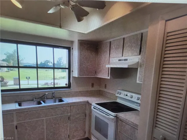 Kitchen featuring white electric range oven, a ceiling fan, and light countertops