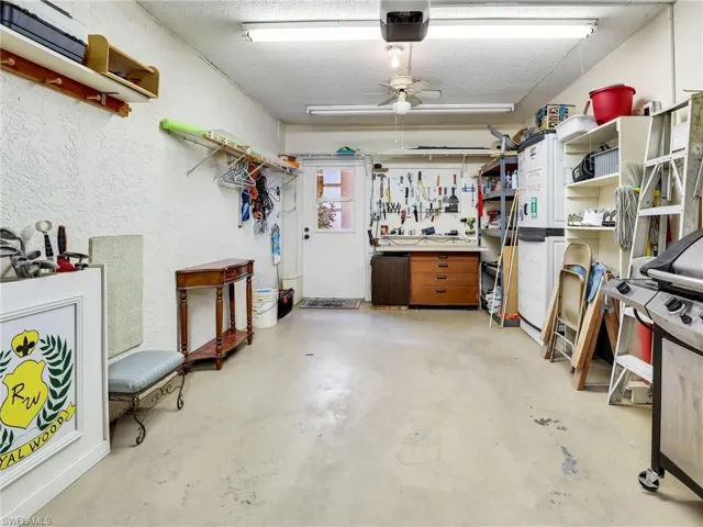 Insid the garage with workbench, mini fridge, storage & a grill