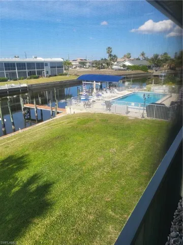 Dock featuring a water view, a yard, a community pool, and a patio