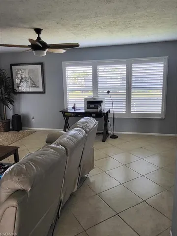 Living area with light tile patterned flooring, a textured ceiling, and ceiling fan