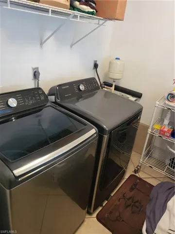 Washroom with light tile patterned flooring and separate washer and dryer