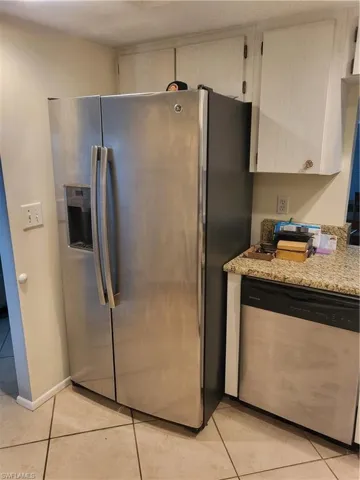 Kitchen featuring appliances with stainless steel finishes, light tile patterned floors, and light stone countertops