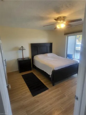 Bedroom with light wood finished floors, access to exterior, a textured ceiling, and ceiling fan