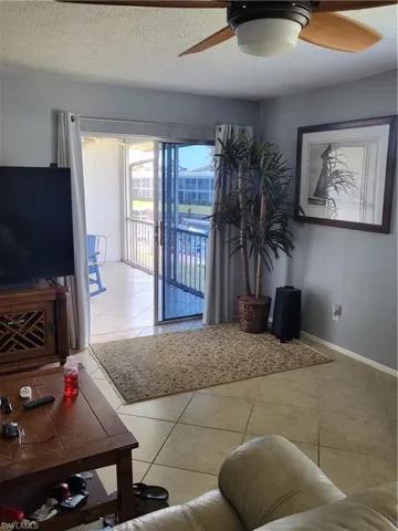 Living area featuring light tile patterned floors, a ceiling fan, and a textured ceiling