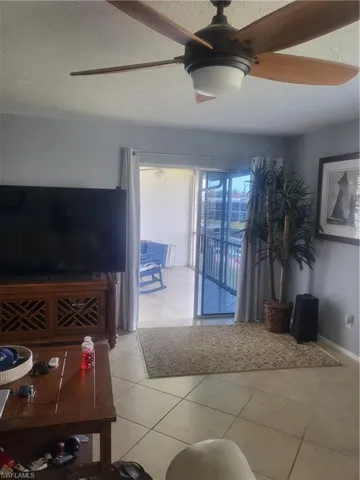 Living area featuring light tile patterned floors, a textured ceiling, and ceiling fan