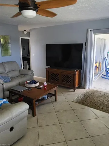 Living area featuring light tile patterned floors, a ceiling fan, and a textured ceiling