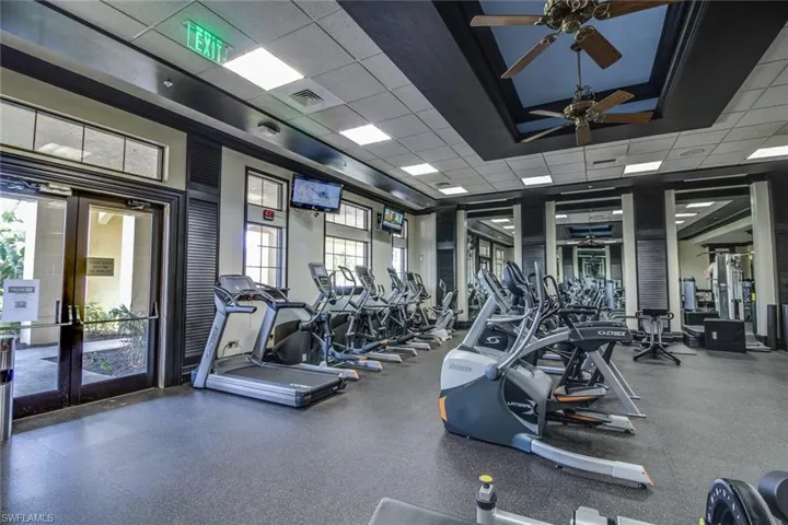 Exercise room featuring a tray ceiling, a drop ceiling, french doors, and ceiling fan