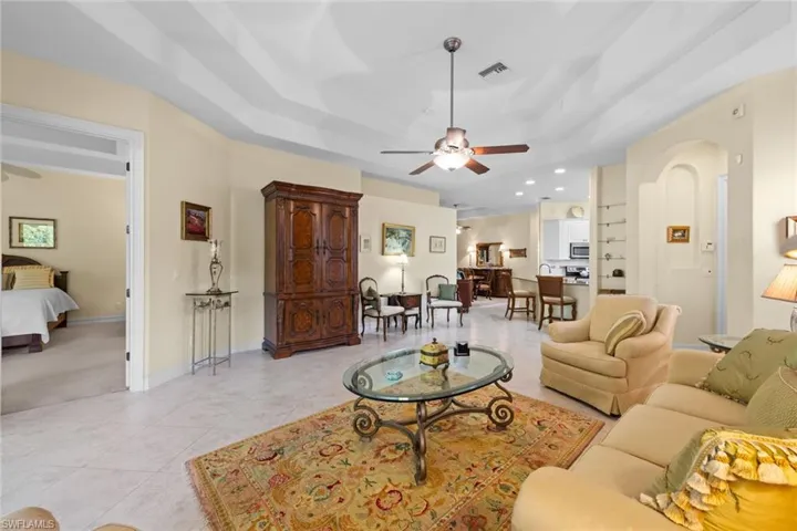 Living room featuring built in shelves, and tray ceiling with ceiling fan