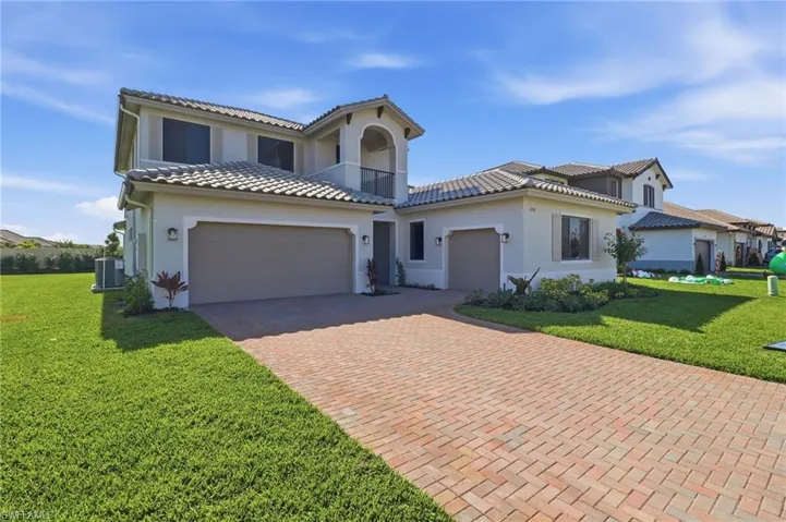 Mediterranean / spanish-style house featuring a front lawn, a garage, decorative driveway, and stucco siding