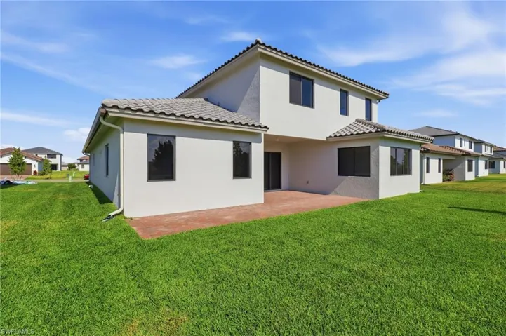 Rear view of house with stucco siding, a patio area, and a yard