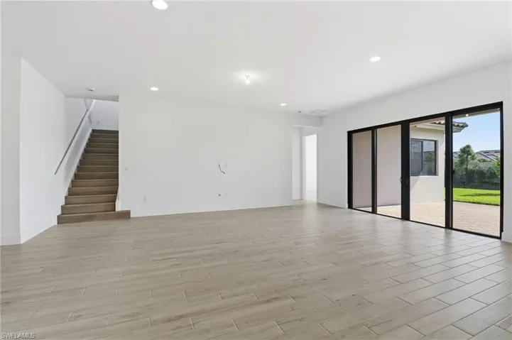 Unfurnished living room featuring wood finish floors, recessed lighting, and stairs