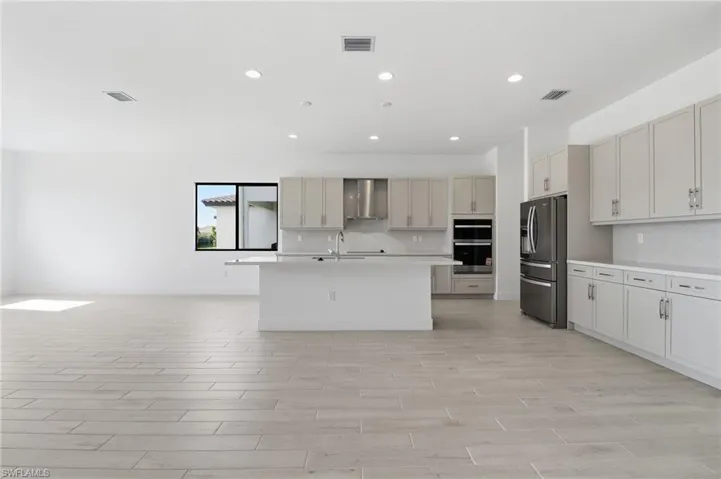 Kitchen featuring a kitchen island with sink, stainless steel appliances, open floor plan, recessed lighting, and wood finish floors