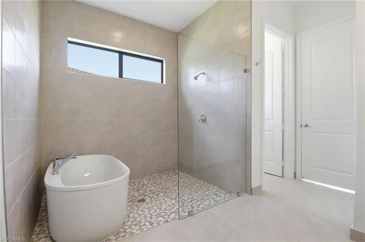 Bathroom featuring a walk in shower, tile patterned floors, and a soaking tub