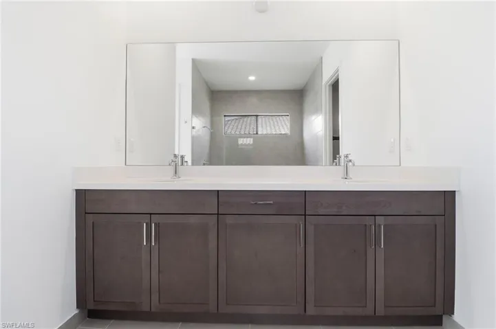 Full bathroom with double vanity and light tile patterned floors