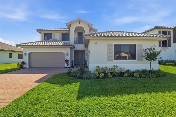 Mediterranean / spanish-style house with stucco siding, decorative driveway, a front lawn, and an attached garage