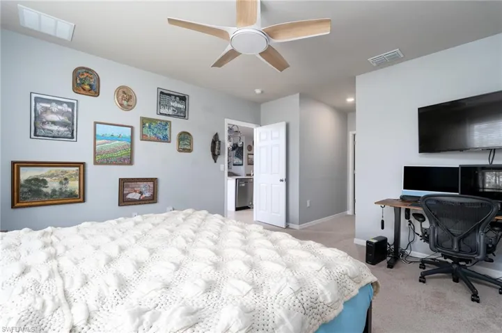 Bedroom featuring light colored carpet, an office area, and ceiling fan