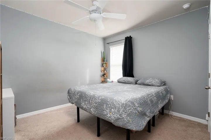 Carpeted bedroom with ceiling fan and baseboards