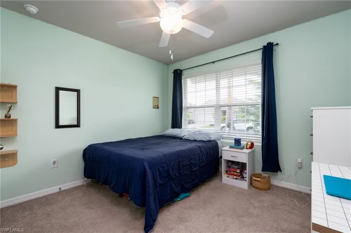 Carpeted bedroom featuring ceiling fan and baseboards