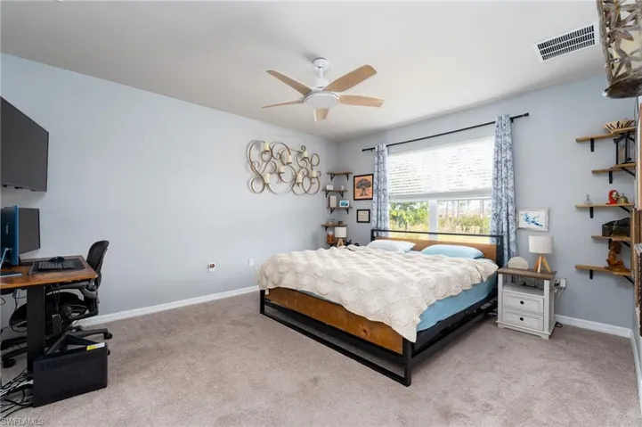 Bedroom featuring an office area, light carpet, and ceiling fan