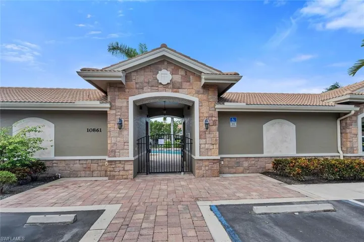 Doorway to property with a tiled roof, uncovered parking, stucco siding, and a gate