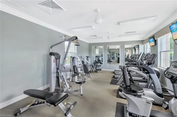 Gym with ornamental molding and a ceiling fan
