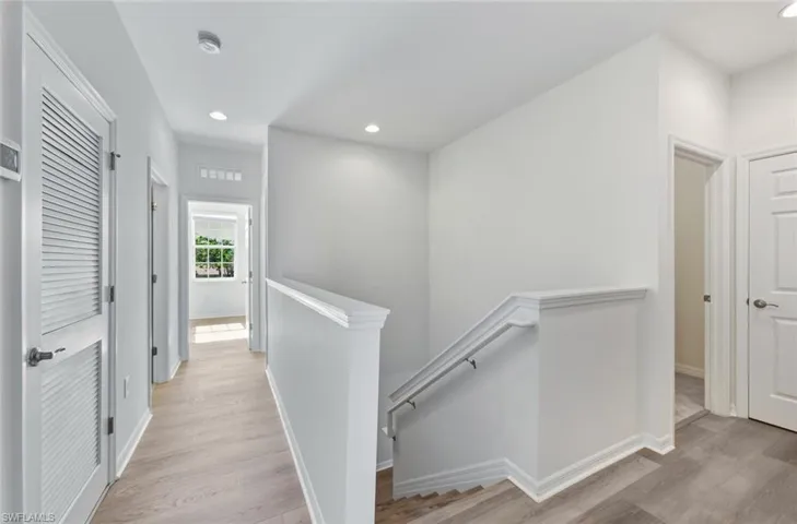 Corridor with an upstairs landing, recessed lighting, and light wood finished floors