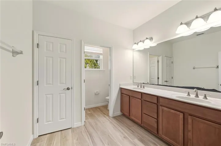 Full bathroom featuring double vanity and wood finish floors