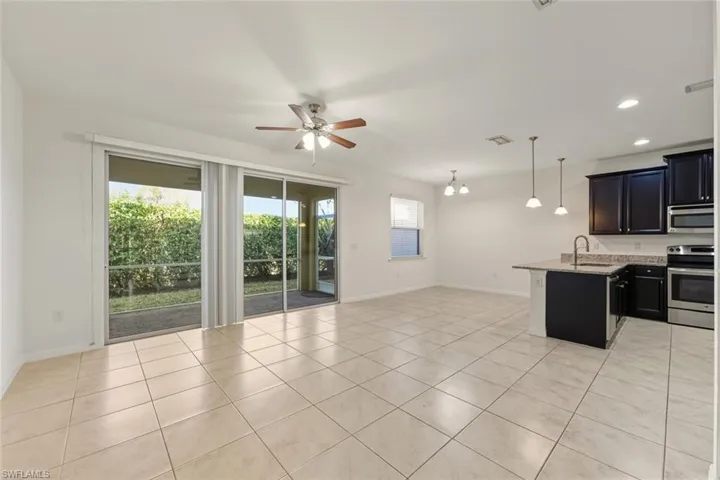 Kitchen featuring pendant lighting, open floor plan, stainless steel appliances, a chandelier, and a ceiling fan