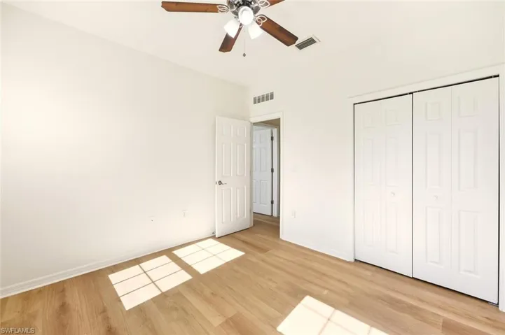 Unfurnished bedroom featuring light wood-style flooring, a closet, and a ceiling fan