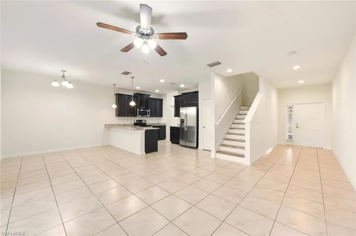 Kitchen with open floor plan, dark cabinetry, stainless steel appliances, a ceiling fan, and a chandelier