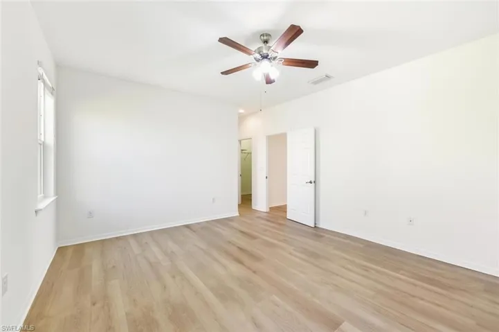Unfurnished bedroom with a ceiling fan, light wood-style flooring, and a spacious closet