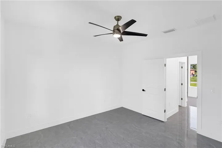 Spacious room featuring large format grey tile flooring, bright white walls, and a contemporary ceiling fan with integrated lighting