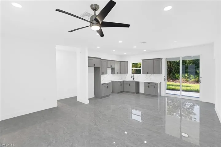 Spacious open-concept living area featuring large format tile flooring, a modern ceiling fan, and recessed lighting