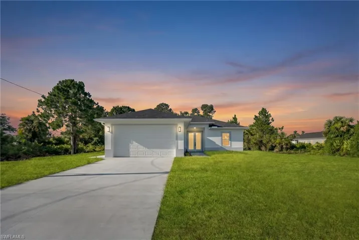 Contemporary single-story residence featuring a two-car garage, concrete driveway, and a manicured lawn