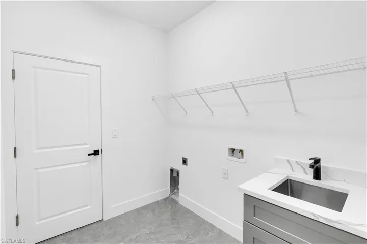 Laundry area featuring a utility sink with a matte black faucet, grey cabinetry, and white countertop with veining
