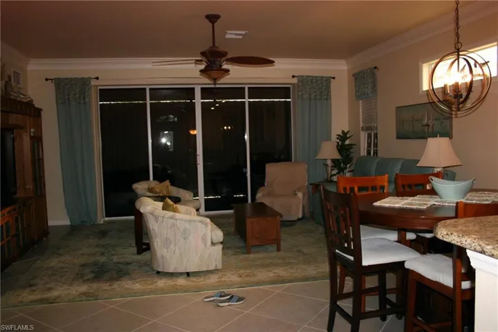Dining space with ornamental molding, tile patterned floors, ceiling fan, and a chandelier