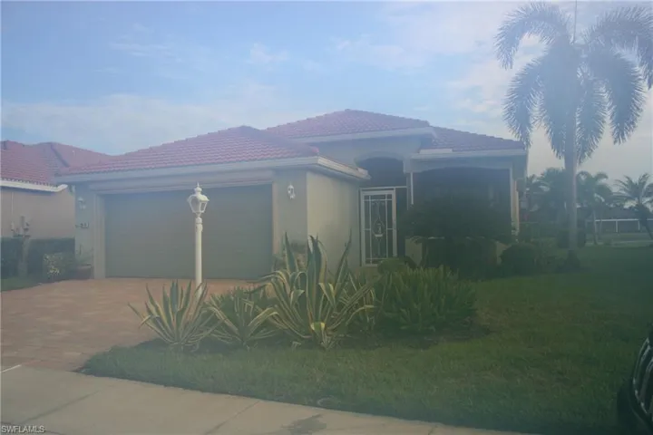 Mediterranean / spanish home with a garage, decorative driveway, stucco siding, a front lawn, and a tiled roof