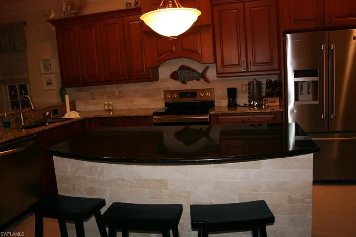 Kitchen with stainless steel appliances, dark stone counters, a breakfast bar, and backsplash