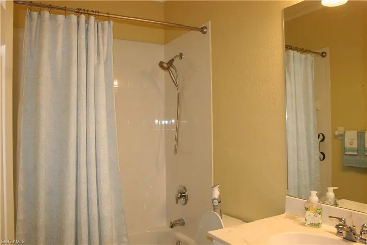 Full bath featuring a textured wall, vanity, and shower / bathtub combination with curtain